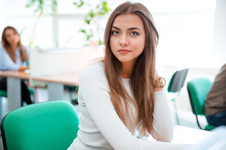 Portrait of a beautiful female student sitting at the table in universityの写真素材