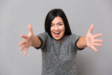 Young beautiful happy smiling in gray jumper looking at camera woman with an open hands ready for huggingの写真素材