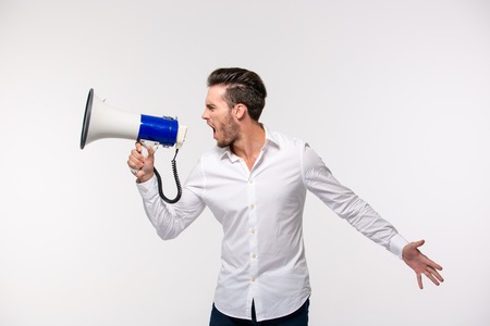 Portrait of a man screaming in megaphone isolated on a white backgroundの写真素材
