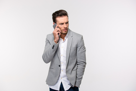 Portrait of a casual young businessman talking on the phone isolated on a white backgroundの写真素材
