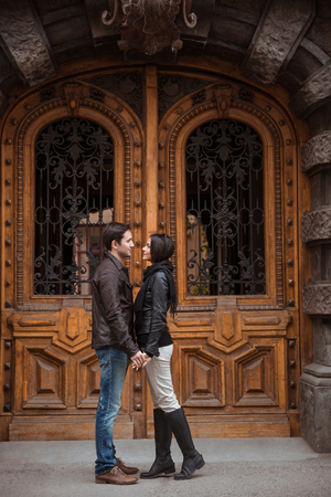 Full length portrait of a young couple flirting outdoors with old wooden door on backgroundの写真素材