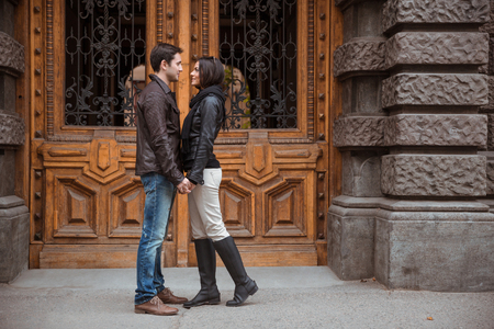 Portrait of romantic couple standing outdoors with old wooden door on bacgroundの写真素材