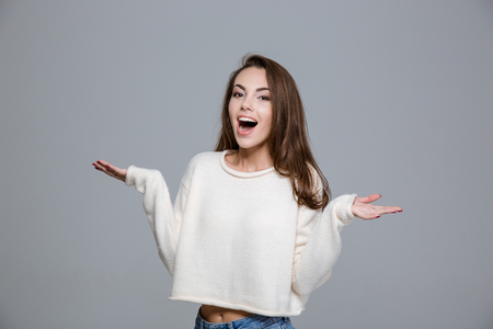 Portrait of a laughing woman holding copyspace on the palms over gray background and looking at cameraの写真素材