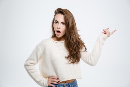Portrait of a young amazed woman pointing finger away isolated on a white backgroundの写真素材