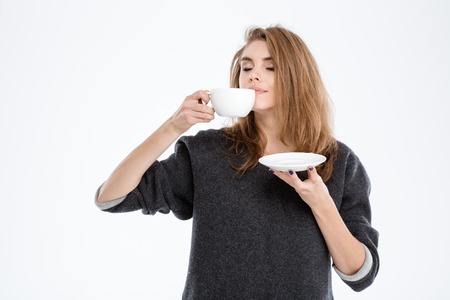 Portrait of a beautiful woman smelling cup with coffee isolated on a white backgroundの写真素材