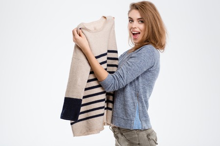 Portrait of a cheerful woman holding sweater isolated on a white backgroundの写真素材