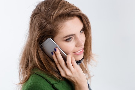 Closeup portrait of a smiling young woman talking on the phone isolated on a white background