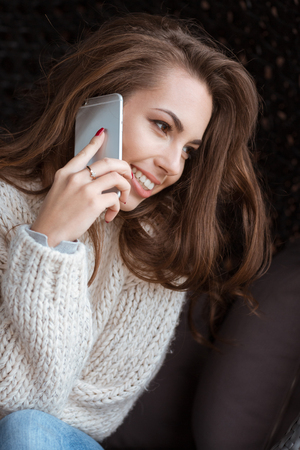 Positive beautiful female talking on cell phone and smileの写真素材