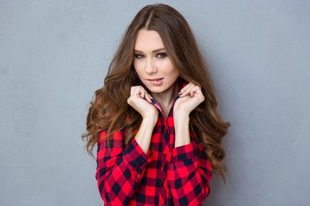 Portrait of a beautiful young woman with curly hair in plaid shirt biting her lipsの写真素材