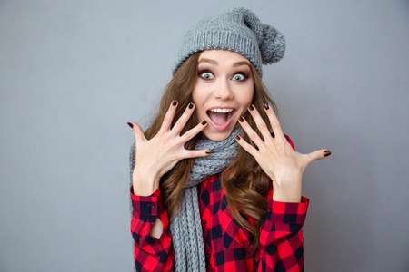 Portrait of a cheerful amazed woman looking at camera over gray backgroundの写真素材