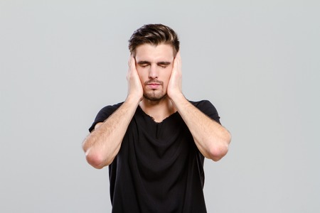 Young handsome attractive man closed his eyes and ears by hands