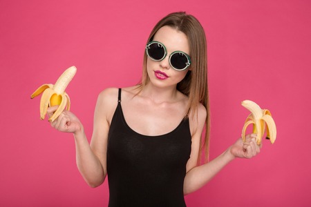 Pretty sensual attractive tender young female in sunglasses holding two bananasの写真素材