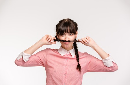 Portrait of a funny woman doing mustache with pigtail isolated on a white backgroundの写真素材