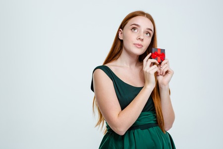 Portrait of a young redhair woman holding jewelry box and dreaming isolated on a white backgroundの写真素材