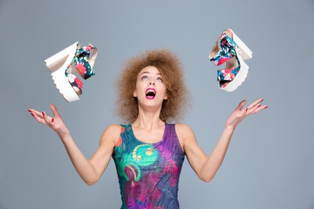 Excited carefree surprised contnt joyful curly young woman amazed about flying shoesの写真素材