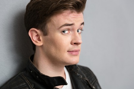 Closeup portrait of a young man looking at camera over gray background