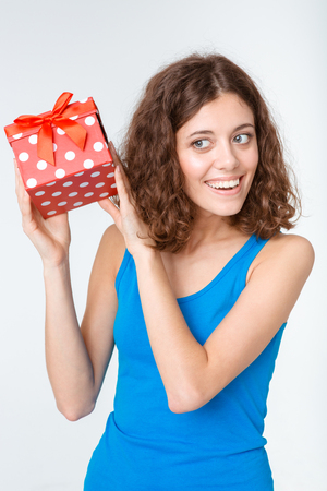 Portrait of a smiling young woman holding gift box isolated on a white backgroundの写真素材