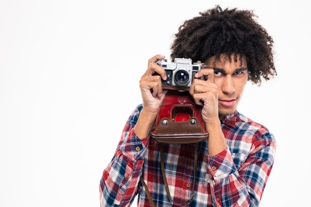 Portrait of a young afro american man making photo on retro camera isolated on a white backgroundの写真素材