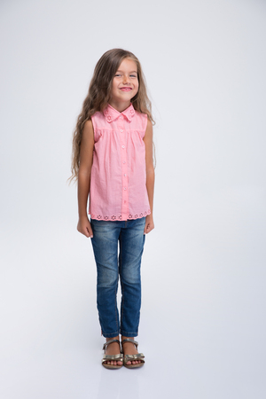 Full length portrait of a smiling cute little girl standing isolated on a white backgroundの写真素材