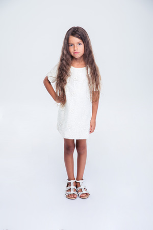 Full length portrait of a pretty little girl in dress standing isolated on a white backgroundの写真素材