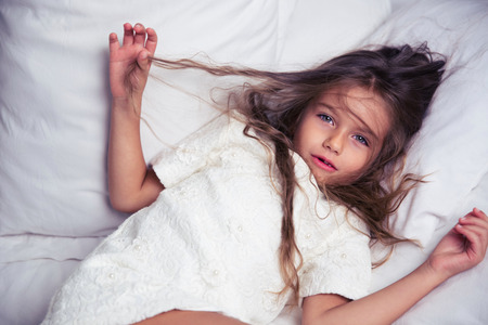 Portrait of a little girl lying in bed at homeの写真素材
