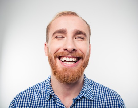 Closeup portrait of a casual man laughing isolated on a white backgroundの写真素材