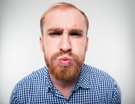 Portrait of a funny young man inflate his cheeks isolated on a white backgroundの写真素材