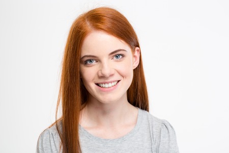 Portrait of positive cheerful young female with long red hair looking at camera isolated over white backgroundの写真素材