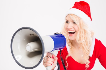 Funny amusing blonde woman in santa claus costume and hat talking in speaker over white backgroundの写真素材