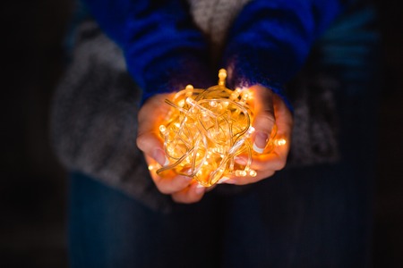Closeup portrait of a female hands holding holidays lightsの写真素材