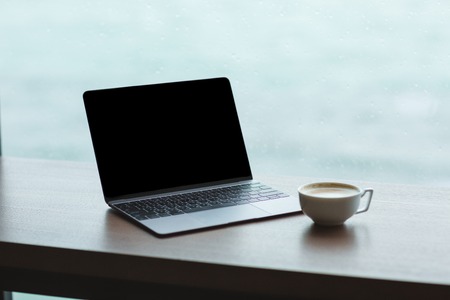 Close up of laptop computer with blank screen and cup of coffee on the table Close up of laptop computer with blank screen and cup of coffee on the table