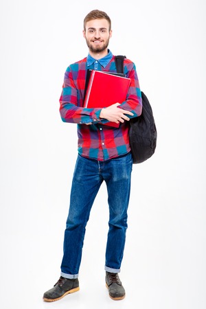 Full length portrait of a happy male student holding books standing isolated on a white backgroundの写真素材