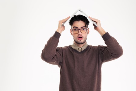 Portrait of a shocked man holding laptop computer over his head isolated on a white background