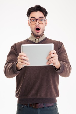 Portrait of a shocked man using tablet computer isolated on a white backgroundの写真素材
