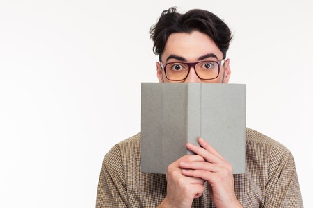 Portrait of a young man covering his face with book isolated on a white backgroundの写真素材