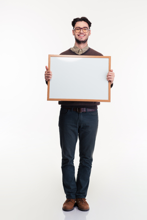 Full length portrait of a smiling man holding blank board isolated on a white backgroundの写真素材
