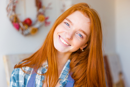 Portrait of beautiful happy young woman with long red hair looking camera and smilingの写真素材