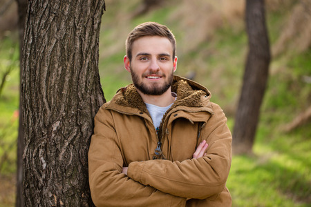 Portrait of a smiling man standing with arms folded outdoors and looking at cameraの写真素材