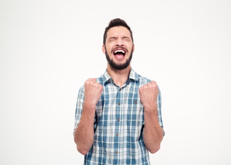 Excited elated happy bearded young male in checkered shirt celebrating success over white backgroundの写真素材
