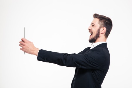 Portrait of a laughing businessman doing video call on tablet computer isolated on a white backgroundの写真素材