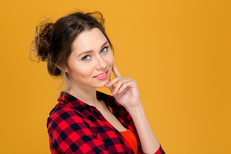 Close up portrait of beautiful smiling young woman in checkered shirt isolated over yellow backgroundの写真素材