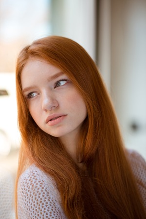 Portrait of a young redhead woman looking at window