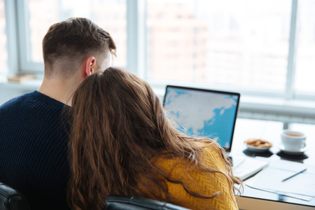 Back view portrait of a couple using laptop computer at home