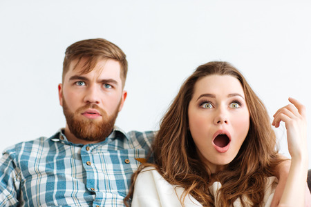 Portrait of a shocked couple looking TV at homeの写真素材