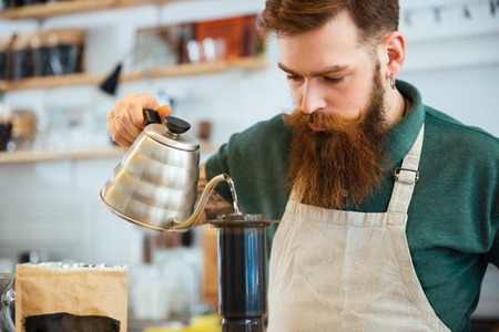 Barista pouring water on coffee ground with filter in coffee shopの写真素材