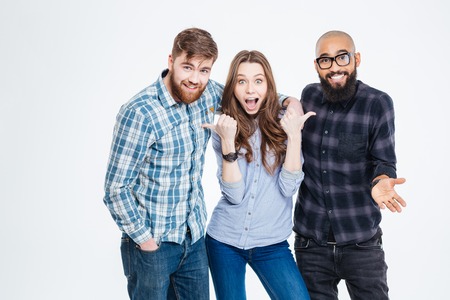 Beautiful amazed young woman standing and pointing on her two bearded handsome friends