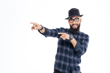 Cheerful young african man with beard in black hat and glasses pointing away with both handsの写真素材