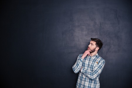 Portrait of a thoughtful man looking up at copyspace over black background