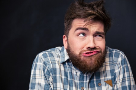Closeup of crazy young man in plaid shirt joking and grimacing over black background