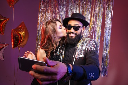 Multiethni? young couple kissing and taking selfie over purple backgroundの写真素材